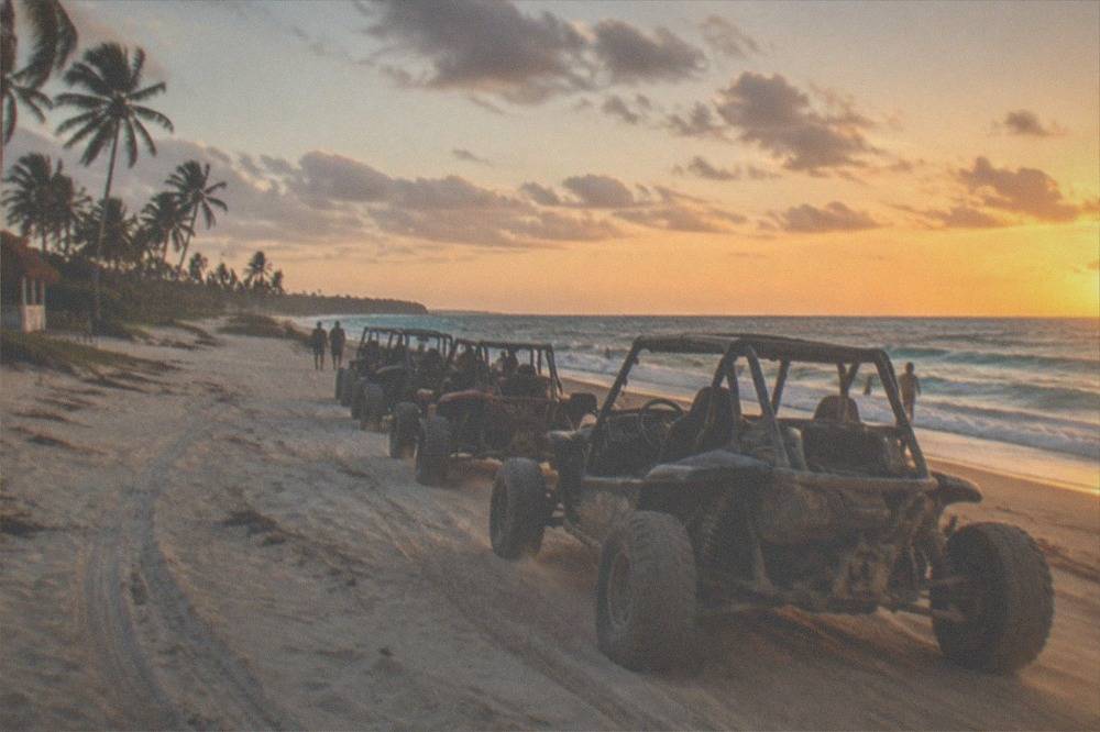 A buggies convoy lined up on the sand at a wide open beach