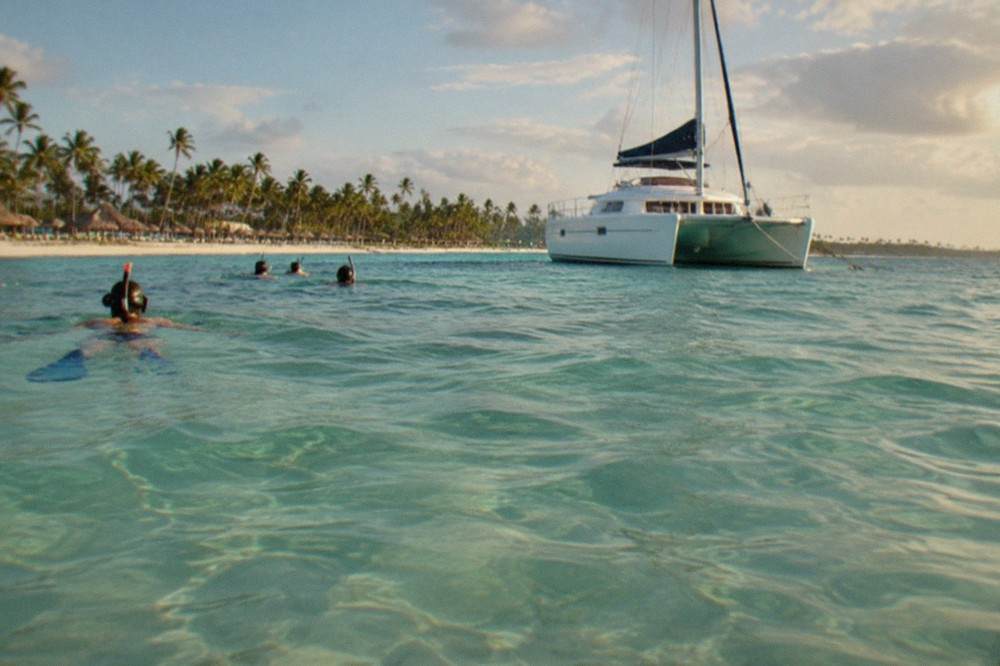 Passengers snorkeling near a catamaran in crystal-clear Caribbean water