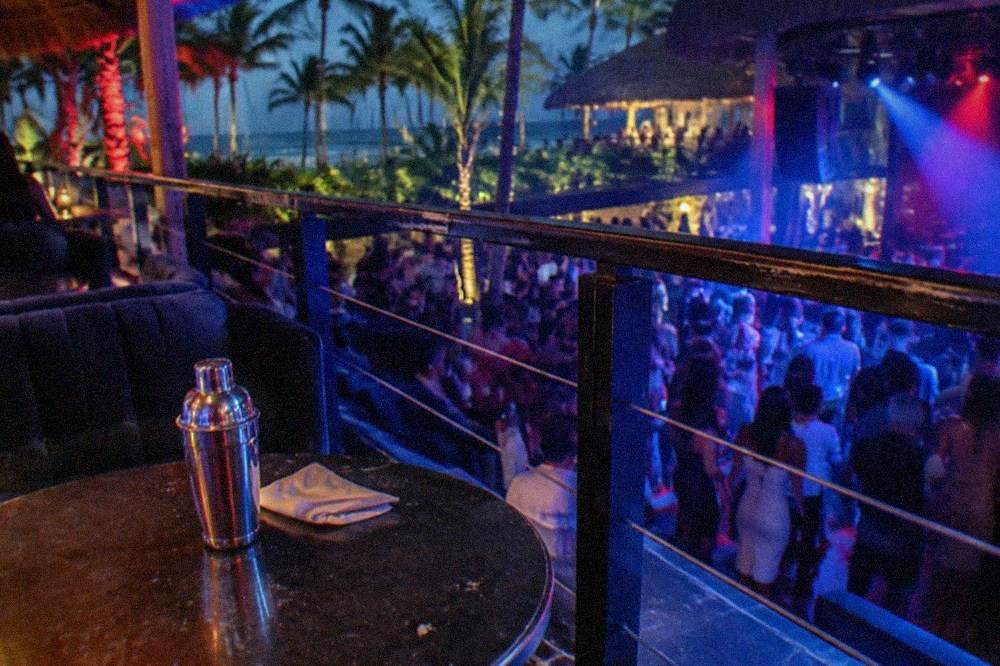 Reserved VIP balcony tables overlooking a nightclub stage lit in blue and red