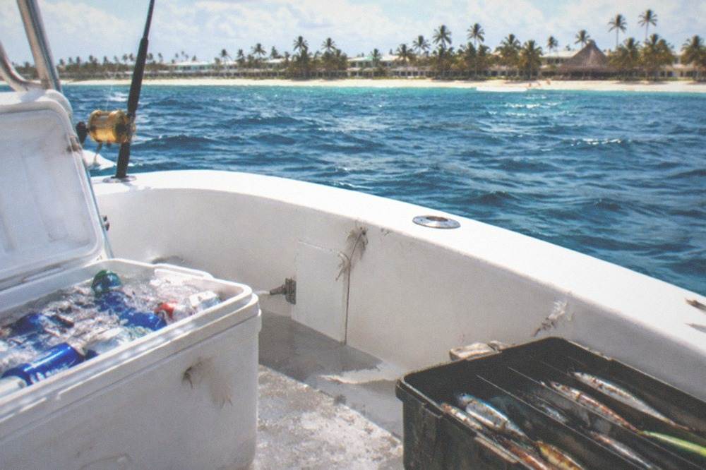 Cooler with drinks and tackle box open on the deck of a fishing charter