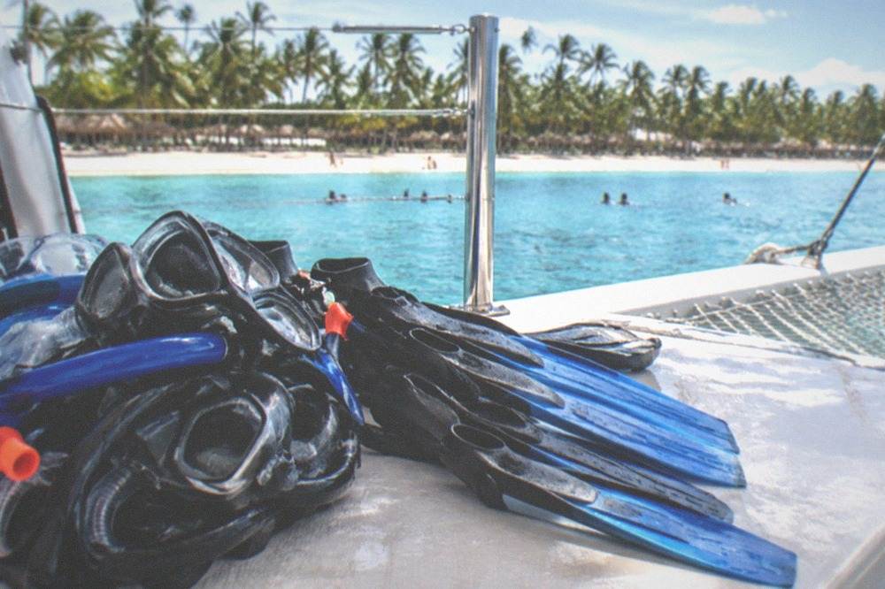 Snorkel masks and fins stacked on the deck of a catamaran ready for a reef stop