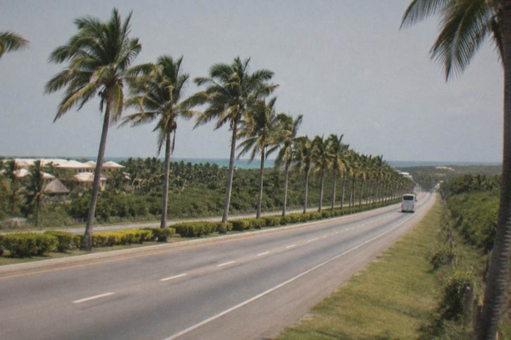 A four-lane tropical highway with palm trees along the shoulder