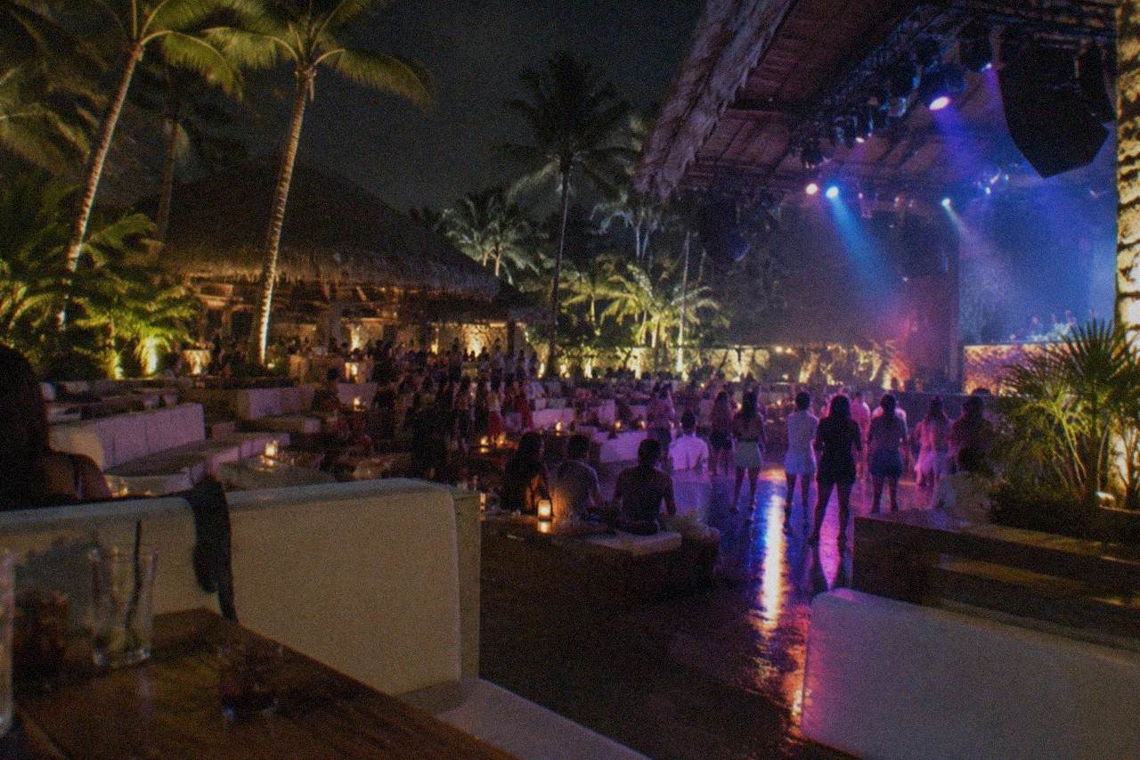 Aerial rigging and stage lights above a crowded floor at a Punta Cana show club, performers on a raised platform.